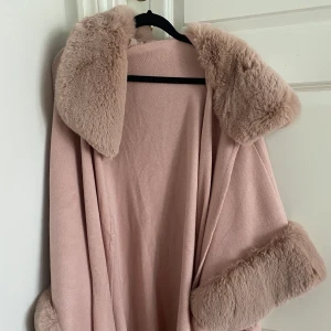 Poncho med päls - En rosa poncho med fake päls. Aldrig använd, köpt på Jackie för 650kr! Säljer nu för 300! Den passar alla men är väldigt stor i sig så skulle säga S/M/L 