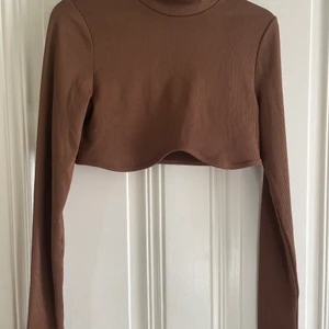 Croppad Tröja  - Hej! Säljer en brun croppad tröja från hm. Färgen Brun! Hål vid armarna för tummen.  Endast använd en gång så som ny. Säljer för den inte kommer till användning. Storlek Medium 