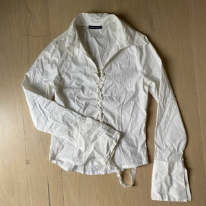 Sexig snörad vit skjorta  - Formar kroppen snyggt och väldigt elastisk. Skulle säga mellan Xs-M. Snörena är lite ”frissiga” men var det vid inköpet. Har aldrig andvänts av mig(köpt second hand)