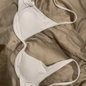 VIT BIKINI TOPP - Hejj! Säljer denna super snygga bikini topp i vitt! Den har typ sån ”stål” aktig band nertill under bysten som går upp i en båge i mitten (se bild.) Super snygg design men säljes då den inte passar mig! Storlek S🫶🏼 Köpt på shein i ett set för 189🫶🏼