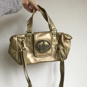 Y2k handväska - Amazing y2k guldväska 💎Måtten är 35x20 cm 🌟Den har lite tecken på användning i form av några slitningar mest undertill och en viss missfärgning inne i fodret. Några rhinestones har trillat av. Men stör inte helheten 💫 Använd gärna köp nu ❄️ Endast frakt 💝