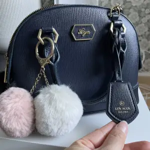 Fin handväska som har använts väldigt sparsamt. Köptni Thailand från märket LYN, otroligt fin kvalitet och känns väldigt lyxig. (Bollarna kan tas bort!) bara en detalj jag själv köpt till!) obs, en dragkedja har fastnat - men annars funkar den bra! :) 
