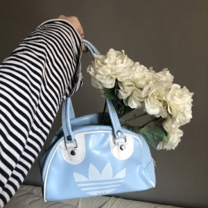 Adidas väska  - Världens sötaste mest underbara lilla blå adidashandväska!    Den har en gul fläck inuti vilket jag misstänker är från tillverkningen (lim eller liknande).    100kr eller bud 