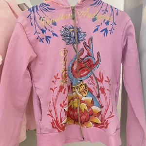 Christian Audigier huvtröja - Vintage Christian Audigier zipup, står strlk 38, uppskattas som S. Jättefint skick!! Dragkedjan är lite trög men funkar bra  