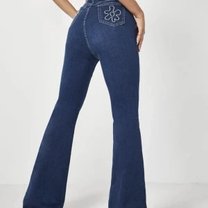 Flared jeans - Högmidjade flared jeans med broderi på bakfickan. Stretchiga