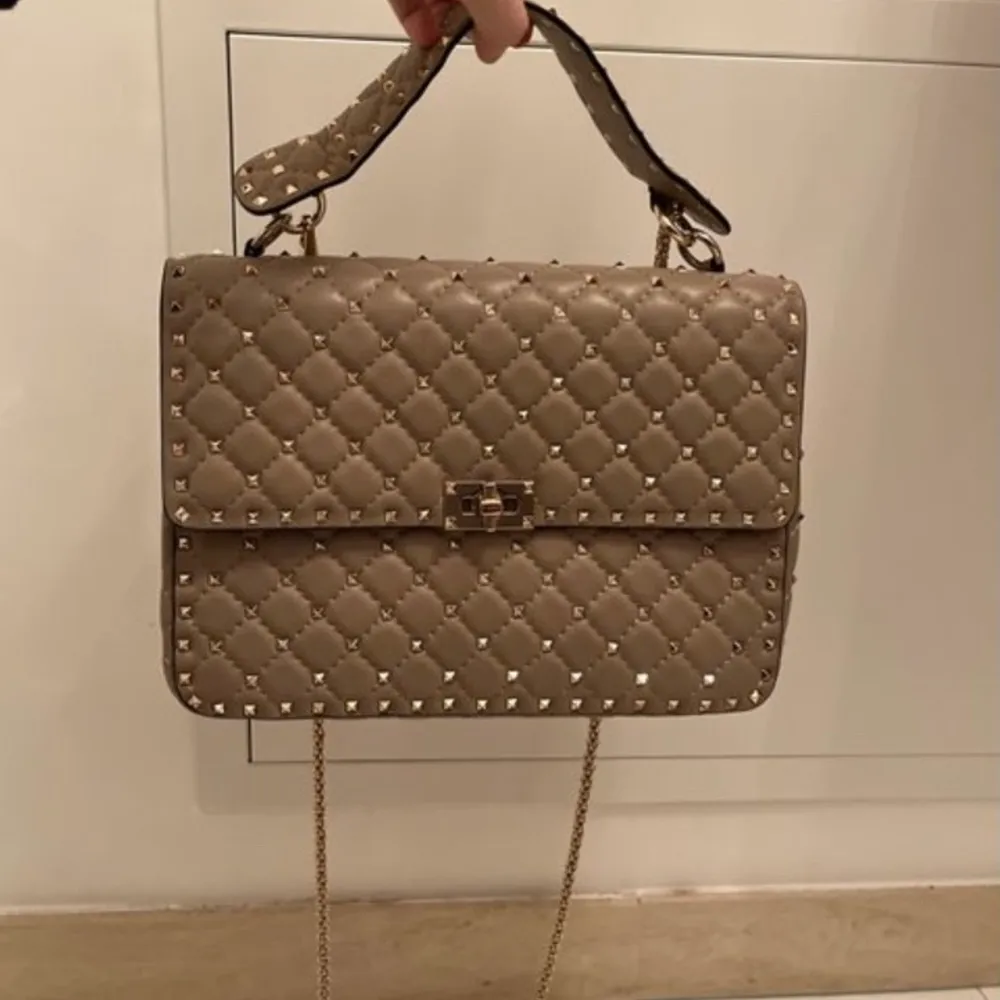 Snyggaste beigea rockstud bagen från valentino garavani💕💕💕 köpt på Vestiaire, har inget äkthetsbevis ifrån valentino men har dustbag och vestiares äkthetsintyg!!! Den har små svarta defekter på insidan men annars är den i väldigt fint skick! Pris kan diskuteras❤️ 20 cm höjd x 29 cm bred❤️. Väskor.