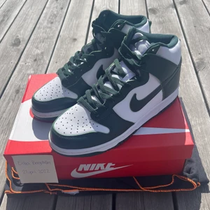 Nike Dunk High Spartan Green - Säljer ett par sprillans nya Nike Dunk High, aldrig använda. Färgen är mörkgrön och det ingår även ett par extra vita snören. Frakt ingår i priset men det går även bra att mötas upp i Växjö eller Jönköping.☺️