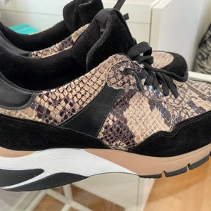 Tamaris skor - Ett par skor från Tamaris. Storlek 38. Ormskinnsmönstrade och mocka. Lite högre sula baktill. Kostade 999 nya använda två gånger så jättefint skick! 