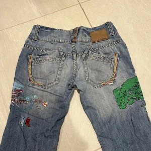Lågmidjade raka jeans med broderi - Lågmidjade raka jeans med broderitryck på fram och baksida i bra skick. Jeansen är från BikBok (vintage) i storlek XS, men jag skulle mer säga att det är stl S/36. Har fler lågmidjade jeans i min profil :)