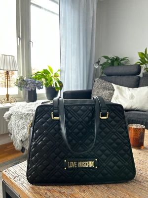 MOSHINO väska - Säljer min skitsnygga Love Moshino väska i superskick. Väldigt sparsamt använd, säljer då jag har en annan väska. Ett stort fack med dragkedja samt två mindre utöver det. Köpt på zalando. Skriv för mer bilder💓