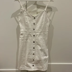 Jeansklänning - Vit jeansklänning i stretch material. Finns dragkedja på sidan. Använd en gång. Inga skavanker.