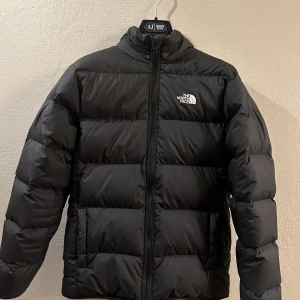 North face dunjacka svart XL junior - Bara legat och skräpat i garderoben pga att jag växt ur den, ändast använd någon enstaka gång och är i nyskick. Passar någon med storlek xs-s i vanlig storlek och kan vändas ut och in