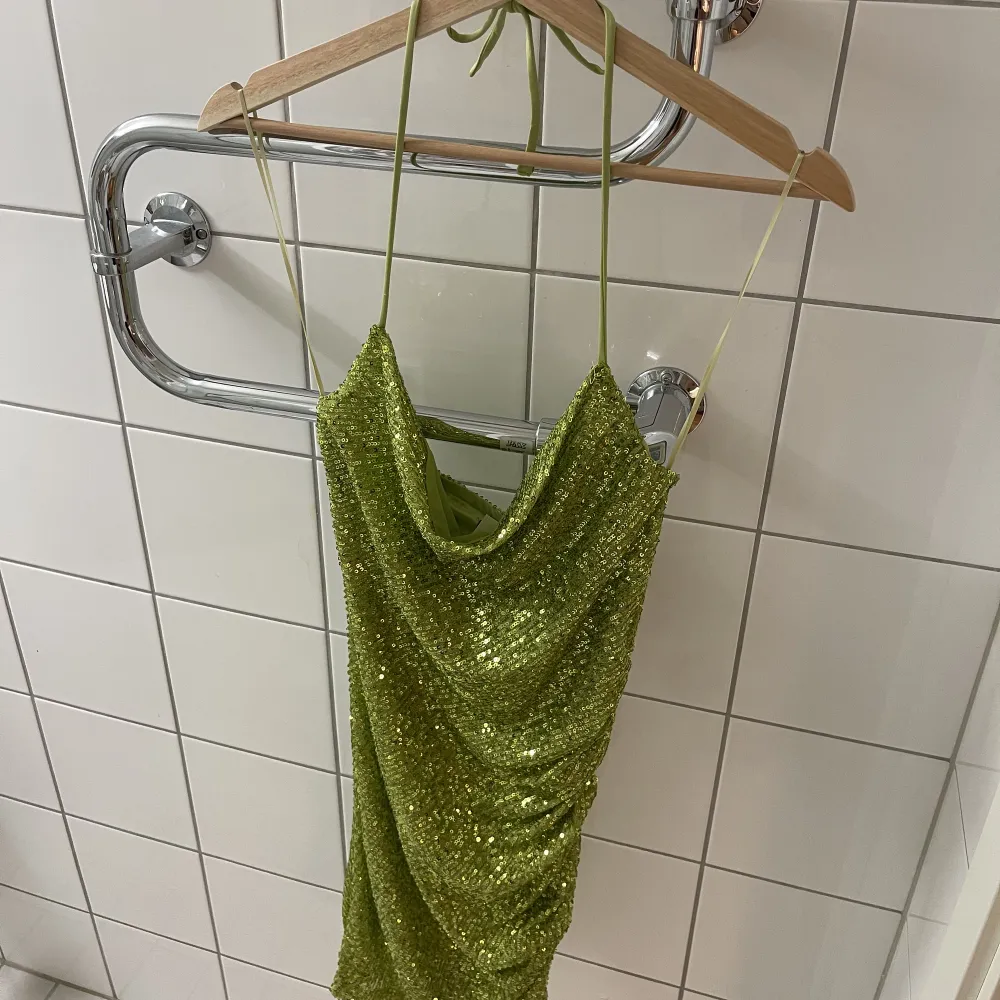 Helt oanvänd klänning från bikbok i glittrande grön och knytning i nacken, storlek XS. Lapparna på! Köpt för 399kr. Klänningar.