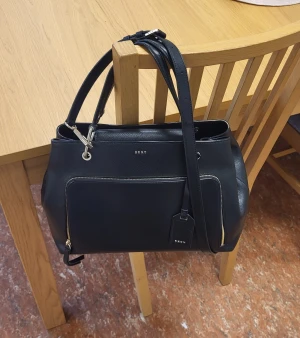 Väska DKNY - Väska från DKNY. I fint skick. Medelstor.   Höjd 24cm Bredd 36cm Djup 17cm Remfall 54cm