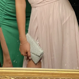 Clutch - Superfin clutch med silvriga stenar. Från glitter. Som ny. Finns en avtagbar silverkedja med så man kan ha den på axeln. Nypris 249kr. Frakt tillkommer. Använd en gång. iPhone plus går ner.