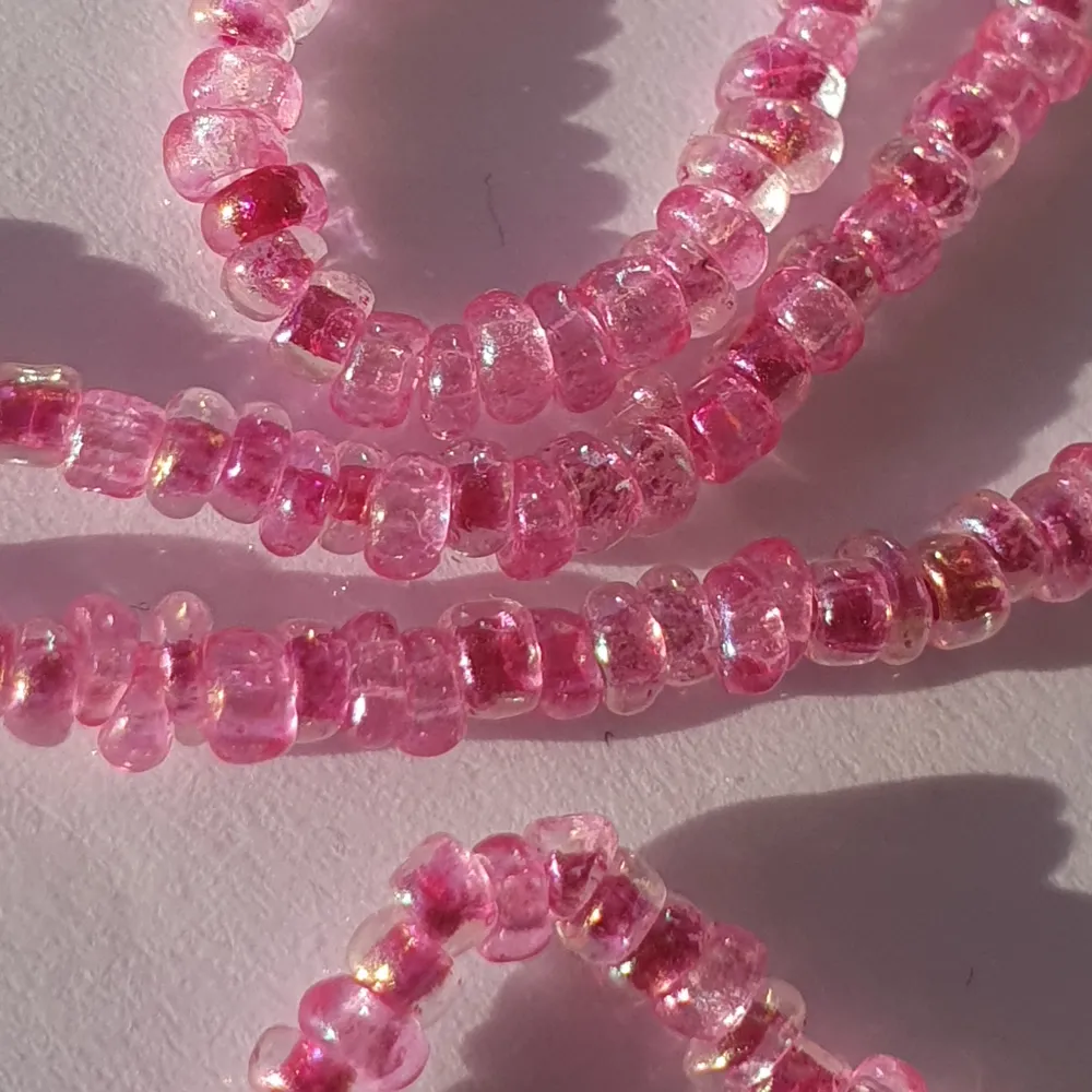 Halsband gjort med rosa glas och plast pärlor med elastisk tråd.. Accessoarer.