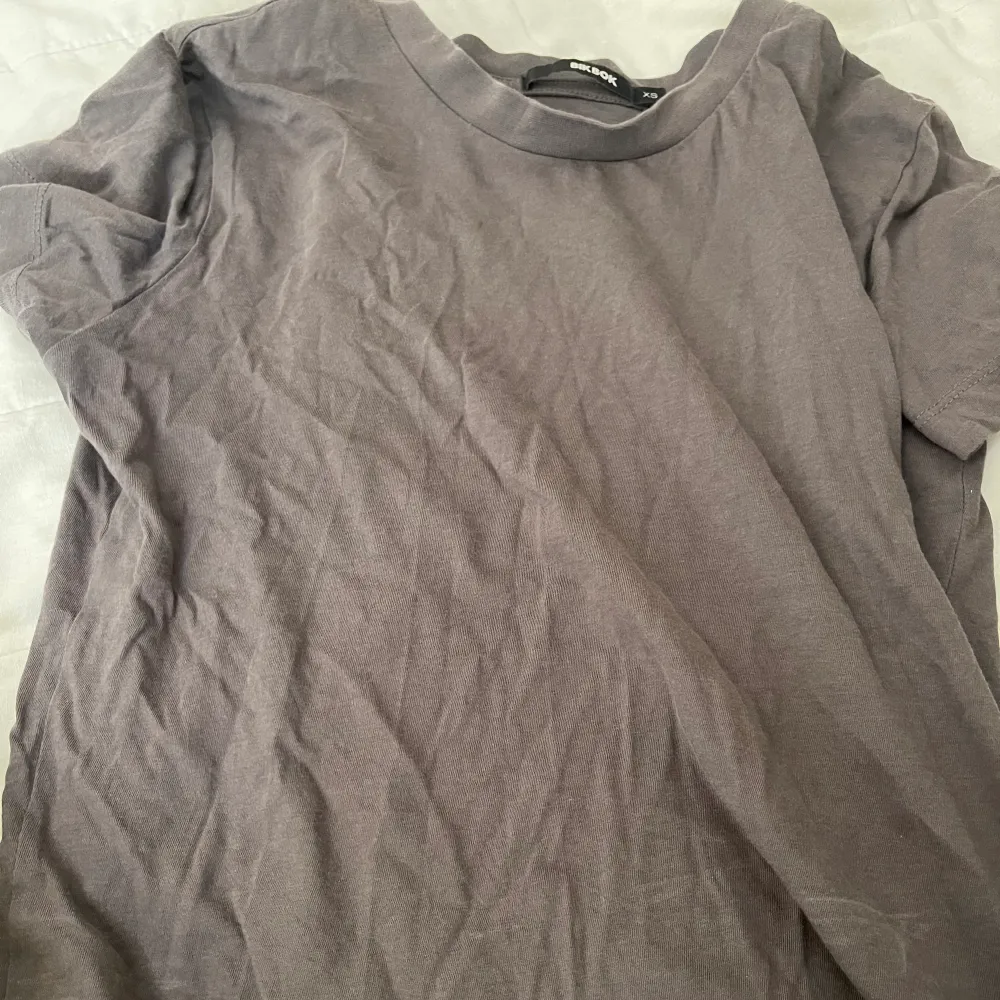 Grå/mörk t-shirt, använd men inga defekter alls. Stl xs, från Gina tricot. Ganska liten i storleken, kort och lite tajt. Köparen står för frakten☺️. T-shirts.