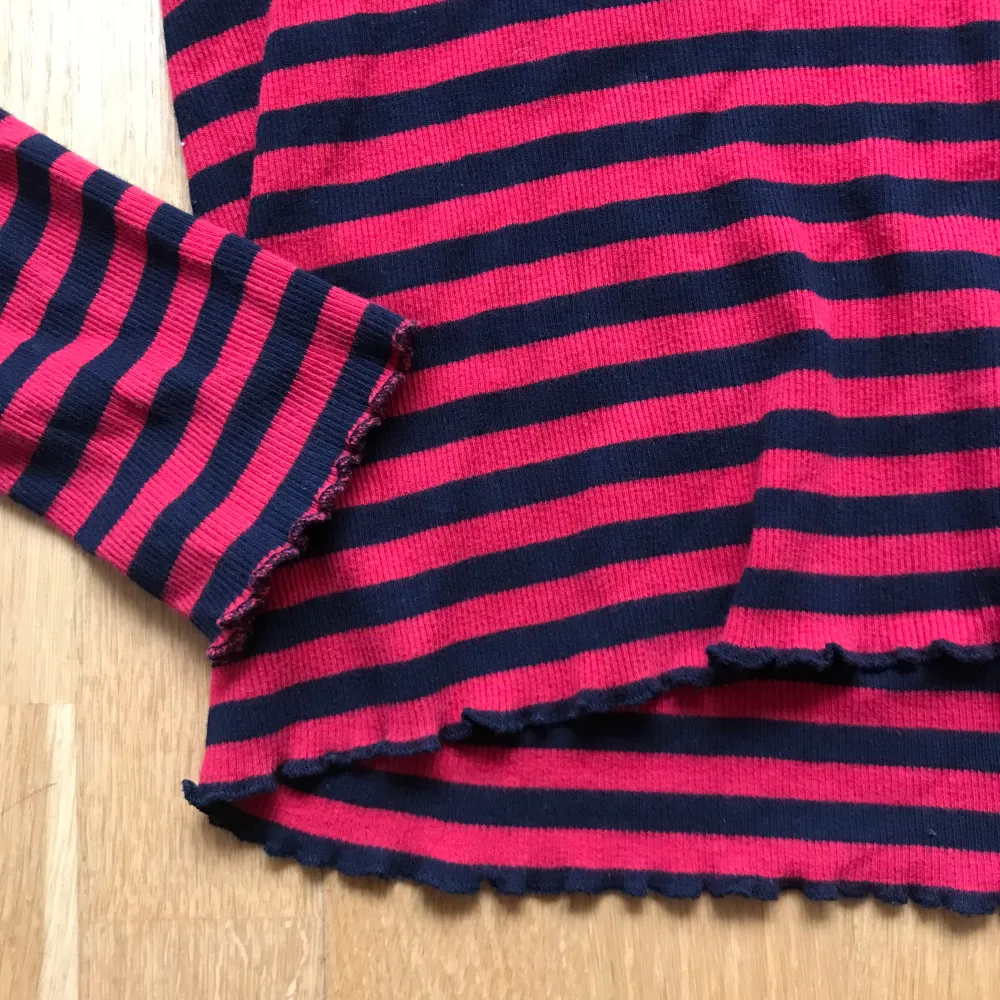 Röd och svart-randig ribbad tröja med volanger nedtill och på ärmarna. Storlek L men passar M/S. Tröjor & Koftor.