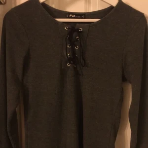 Tröja - Säljer denna tajta ribbade tröjan som aldrig blivit använd. Den är i fint skick med knytning framme vid brösten. Pris 40kr+frakt, om man inte kommer med ett bud💕