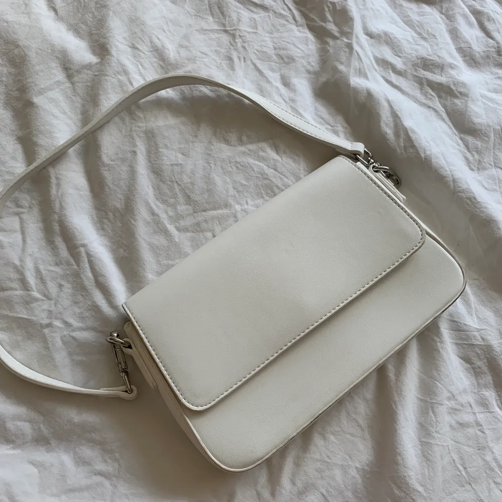 Jättefin vit handväska från Åhléns endast använd en gång på studenten, säljer pga kommer ej till användning.  Den har ett innerfack med dragkejda. Väskor.