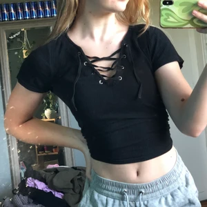 Svart tröja med snörning - En svart mjuk T-shirt med snörning fram från H&M. Strl S 