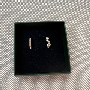 Earcuffs från Safira - 2st earcuffs, Above the clouds earcuff och Swarovski pearl earcuff. Båda har kärna av 925 Sterling Silver och är täckta av en tjock plätering av 18-24 karat guld. Inga repor eller rispor! Boxen användes bara till bilderna hör ej till. Postas för 25kr! 
