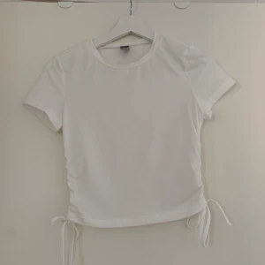 Kroppad vit T-shirt med snören - Säljer nu denna T-shirt med snörning från Shein då den inte passar mig längre. Köparen står för frakten. Betalning sker via swish. Kan skickas med spårbar frakt