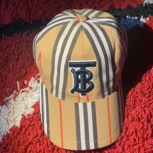 Burberry Keps - Säljer min Burrberry  TB-embroidered Icon-stripe canvas baseball keps för jag har tröttnat på den och använder inte den så mycket har haft den i cirka 2 veckor men bara använt ett par gånger.