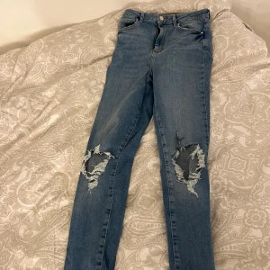 Jeans - Blåa straight jeans med hål på knäna, gott skick använt cirka 3-4 gånger 