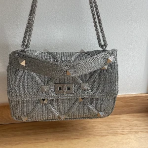 Valentino garavani väska - Valentino Garavani väska i modellen roman stud (Lurex) i silverfärg. Köptes för 28500kr på farfetch, så inga tidigare ägare innan mig. Allt finns till väskan, Kvitto, dustbag, de röda korten. 