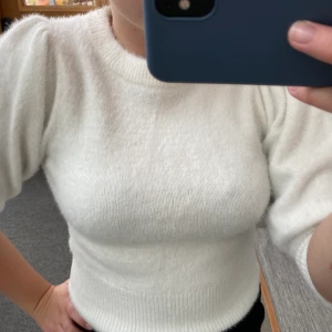 Vit tröja - Vit fin tröja från H&M som slutar vid armbågen. Den har lite puffiga ärmar men sitter annars tight. Jätteskönt och varmt material. Väldigt fint skick. Storlek XS men skulle tro att den passar bra på någon med S också.