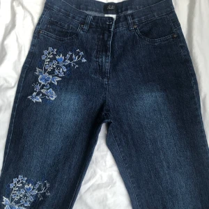 Jeans med blommor  - Jeans med broderade blommor på! Köpt secondhand! Är lite stretchigt material men passar både M och L 