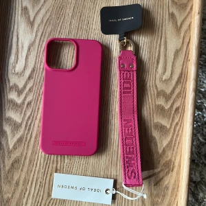 Ideal of Sweden mobilskal m. Band - Ett rosa skalset till iPhone 12/13 Pro Max.