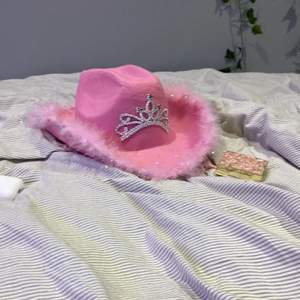 Fin cowboy hatt i färgen rosa. Tiara på och ludd på sidan. Snöret kan justeras! Jätte fin och gullig men säljs pga ingen användning. Fin dekoration i rummet och 🫶🏼 köparen står för frakten 💓