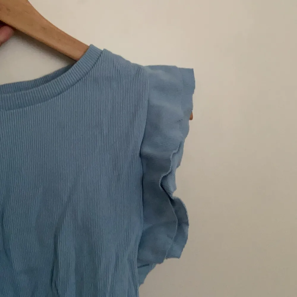 Ljus blå tröja med volanger vid axlarna som jag köpte för mindre än ett år sen men bara använt 2 ggr. Toppar.
