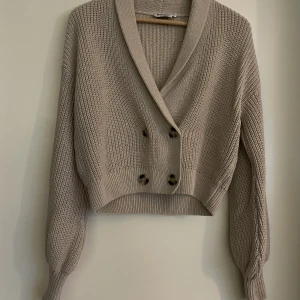 Stickad cardigan  - En stickad cardigan med fina knappar i söt dammrosa färg från NA-KD. Storlek XS. Använde fatal gånger, som ny!