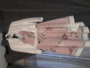 Klänning med ens jacka - Denna klänning, i rosa färg med blommor kommer med sin jacka i en helt vit färg. Plaggerna är helt nya, har sina prislappar fortfarande på sig. De har inte kommit till användning. Strl på de är E46. Plagget är helt nytt och säljer hela för 400kr. 