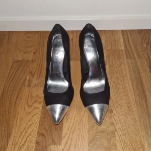 Svarta klackskor med silvrig spets - Klackskor från Lindex. Använda fåtalet gånger knappt!  Svarta med slivrig spets.  Inga repor, inte smutsiga Väldigt bekväma klackskor i storlek 39! Bra passform. Inköpta för 499kr