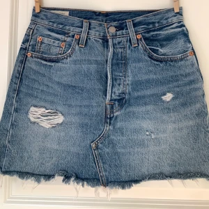 Jeanskjol från Levi’s  - Jeanskjol från Levi’s med lite slitningsdetaljer. Storlek 25, motsvara ungefär xs-s. Den är i mycket bra skick. Färgen är mest verklighetstrogen på sista bilden. Hör av dig vid intresse. Frakt ingår. 