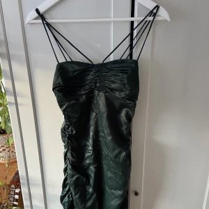 Festklänning - Mörkgrön festklänning från zara, den sitter figurnära och snyggt, perfekt inför julafton eller nyår! Helt oanvänd med prislappen kvar, säljer för 100kr mindre än originalpriset (skriv om ni vill ha bild på hur den sitter)