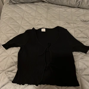 Topp-tröja  - En fin svart tröja. Där fram är det knutar. 134/140.       Lindex