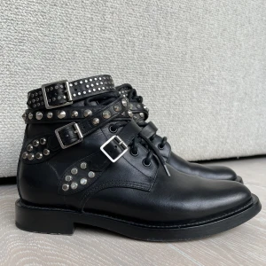 Saint Laurent boots - Svarta biker boots med silver studs från Saint Laurent. Ikonisk modell. Silverfärgade detaljer och läderremmar. Utmärkt skick. Använda endast ett fåtal gånger då de är för små för mig. 100% läder. Originalpris 11.000kr, köpta hos Natalie Schuterman. 