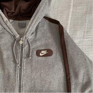 grå nike hoodie med snygga bruna detaljer, snyggt tryck på ryggen. storlek S på lappen men skulle säga S/M. väldigt bra skick!