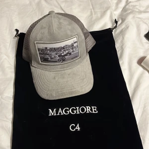 Maggiore keps - Maggiore keps från kollektionen C4, väldigt limiterad keps som sålde slut på minuter. Släpptes ett väldigt limiterat antal av kepsen, skadan går lätt att fixa genom att köpa en ny kepsjusterare dit bak och sy på själv eller hos en specialist
