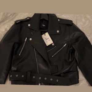Bikbok skinnjacka  - Intressekoll på denna snygga skinnjacka med ett bälte!! Aldrig använd och helt ny från bikbok, nypris 800kr. Den är i storlek S men passar även M☺️