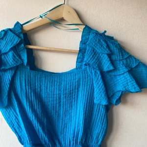 Topp från Gina tricot  - Fin kort topp i härlig blå färg perfekt i sommar, aldrig använd