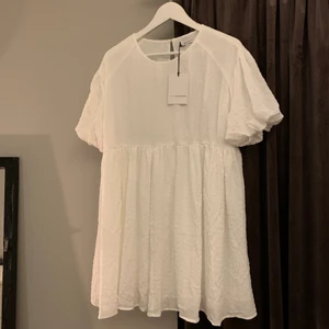 Vit klänning  - Säljer denna sommardröm från Nelly. Köpt i somras och aldrig använd (lapp fortfarande kvar) modellen är vid och oversized så jag skulle rekommendera denna för ca storlek M/38. Sjölv är jag 165 och har storlek XS/S men tycker den satt lite stort på mig