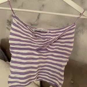 Bershka bandeau topp - Bandeau topp från Bershka i lila vitt mönster. Superskönt typ fik stickat material som är stretchigt☺️ Knappt använd💞
