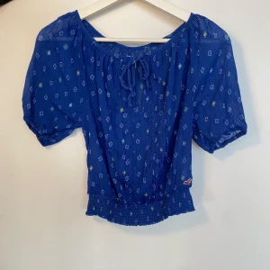 Hollister blommig topp - En blå blommig lätt genomskinlig topp från Hollister.