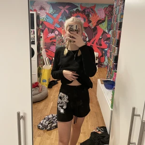 Shorts  - Svarta shorts med en vid drake på ena benet, snörena är fejk!! Aldrig använda så de är i bra skick!